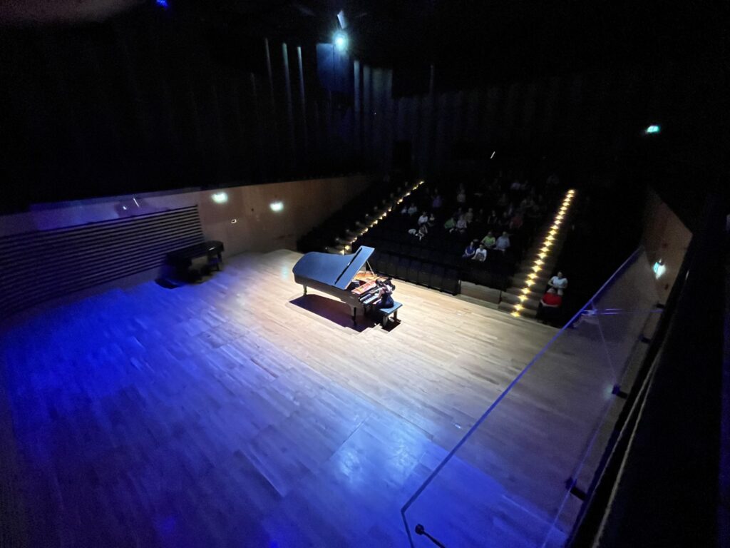 a piano on a stage with people watching