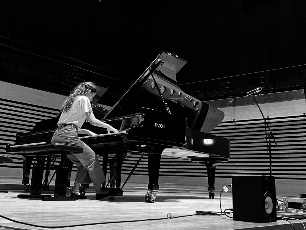 a woman playing piano in a concert hall