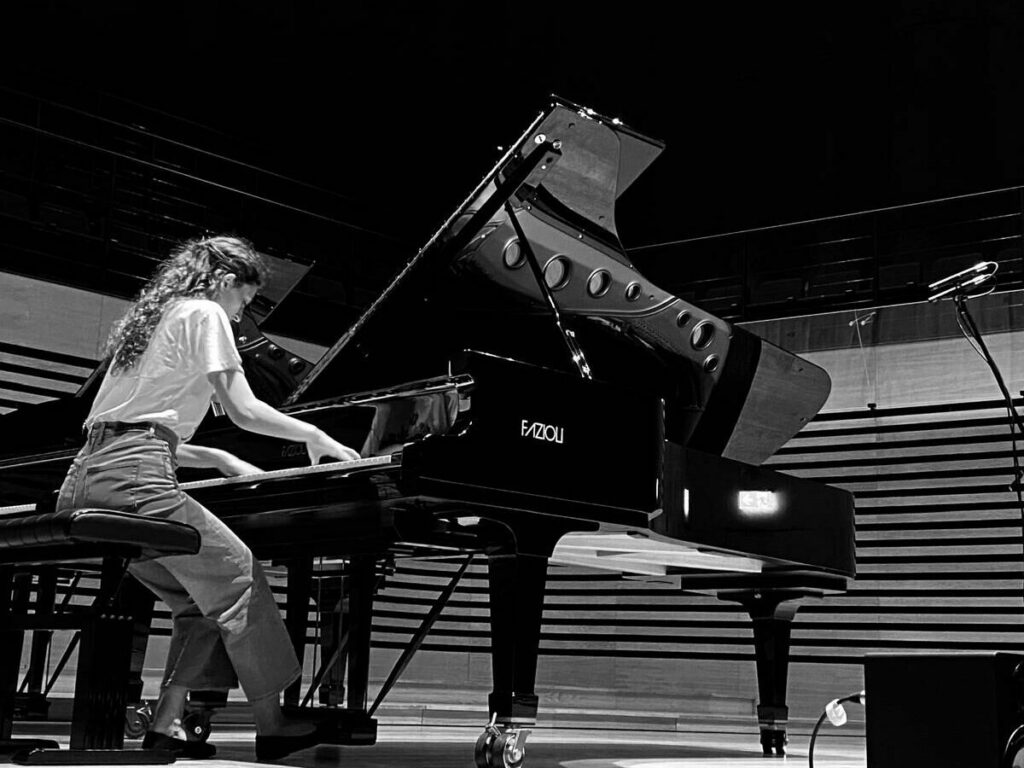 a woman playing piano in a concert hall